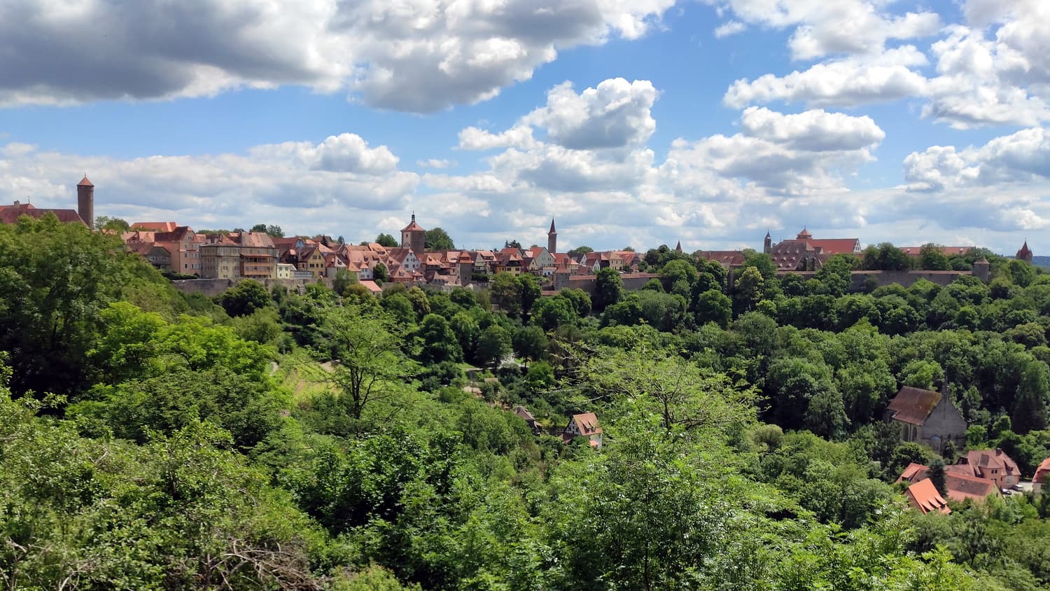 Blick vom Burggarten über das grüne Taubertal auf die Mauern und Türme Rothenburgs