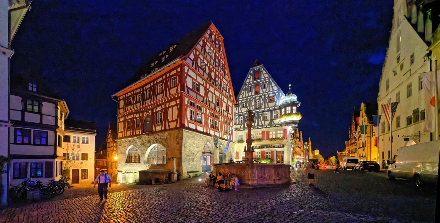Fachwerkhäuser und ein Brunnen auf dem Rothenburger Marktplatz bei Nacht